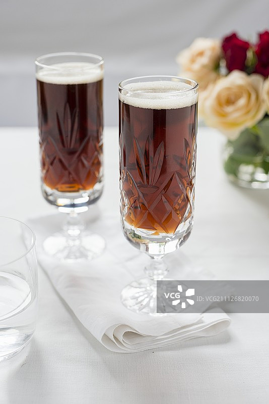 两杯黑啤酒，背景是玫瑰花束图片素材