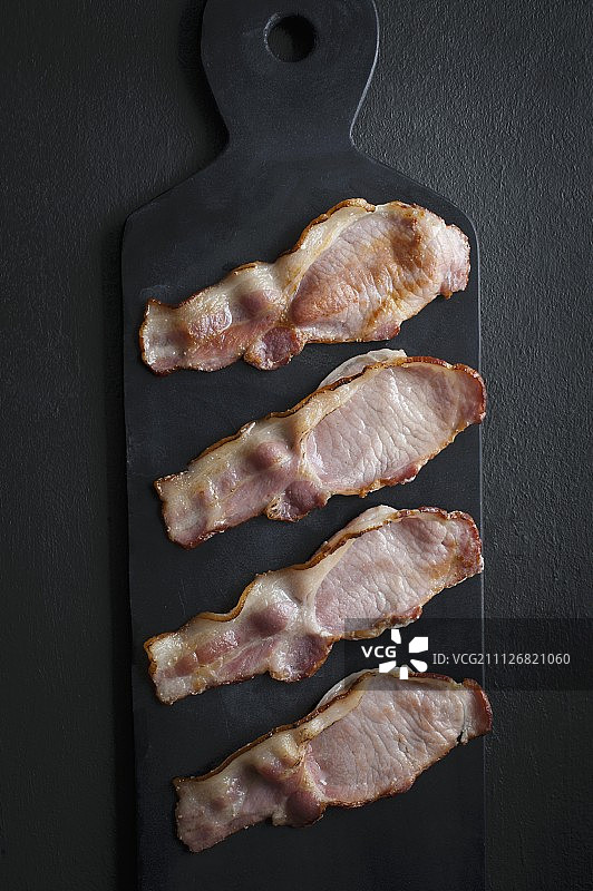 黑色石板盘上的四片培根图片素材