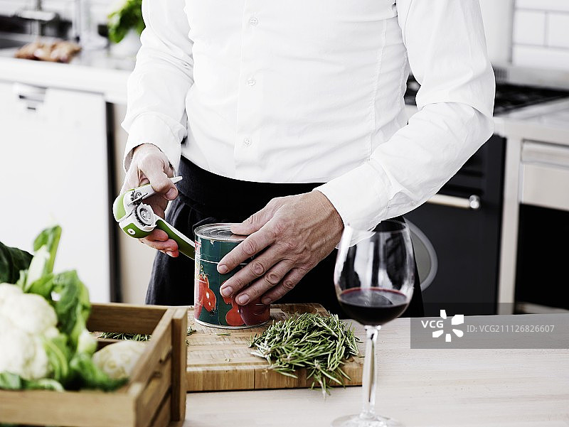 在厨房里打开锡罐头的男人图片素材