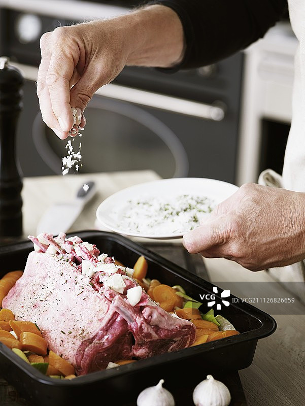 一个男人在烤盘中给排骨调味图片素材