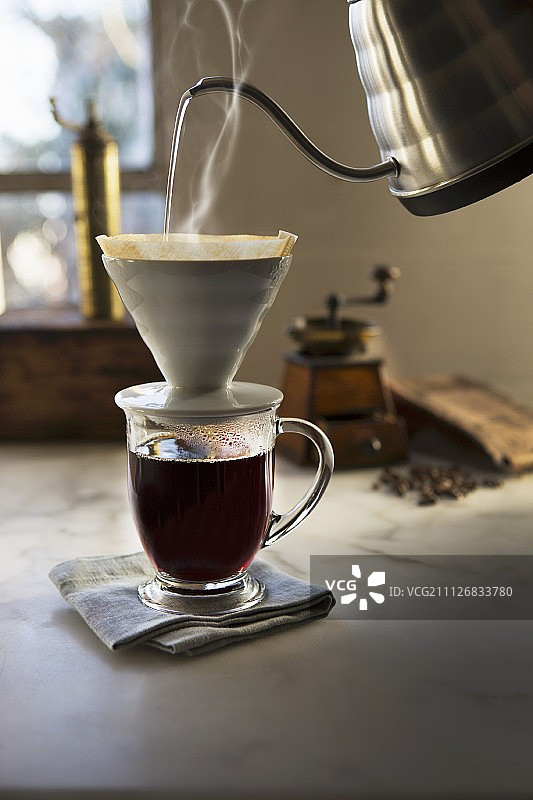 热水通过咖啡滤纸倒入玻璃杯图片素材