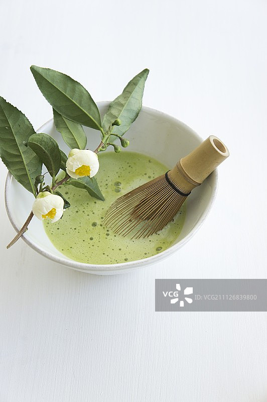 白色表面茶碗中的竹制抹茶和茶图片素材