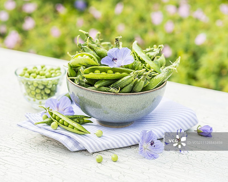 碗中的绿色豌豆荚，置于花园桌上图片素材