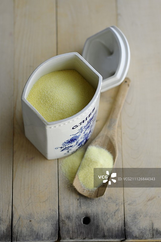 瓷器容器和木勺中的粗粒小麦粉图片素材