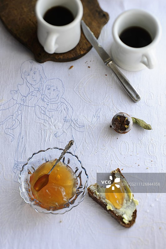 玻璃碗和涂有黄油的面包片上的榅桲果冻图片素材