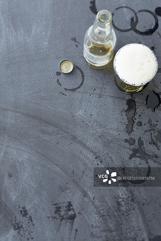 灰色背景上的啤酒杯、瓶子和瓶盖图片素材