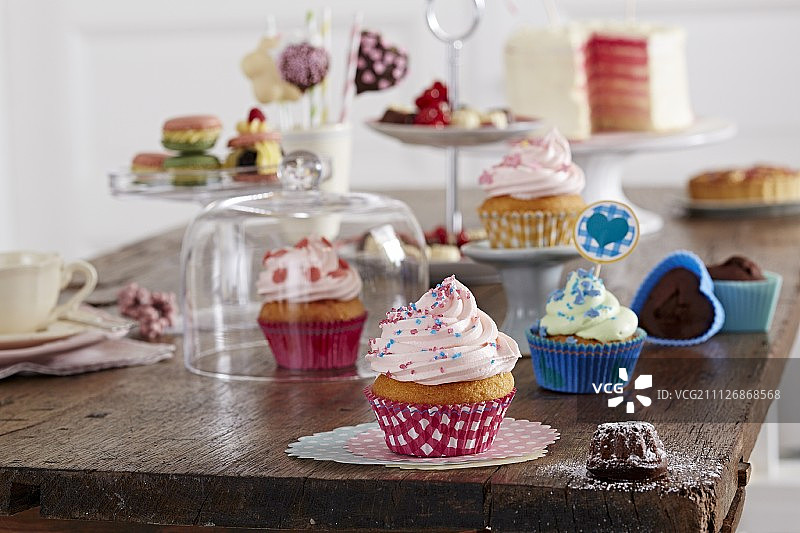 木桌上的各种纸杯蛋糕、糕点和蛋糕图片素材