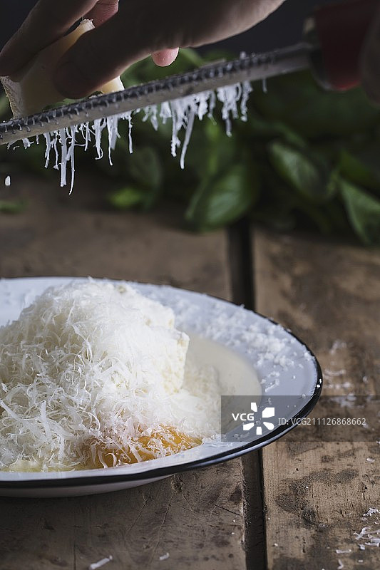 将帕尔马干酪擦入含有意大利乳清干酪、鸡蛋、盐和胡椒粉的碗中，制成意大利面疙瘩图片素材