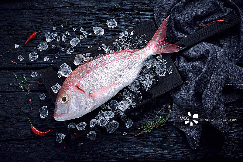 黑色木桌上冰鲜的西班牙鲷鱼图片素材