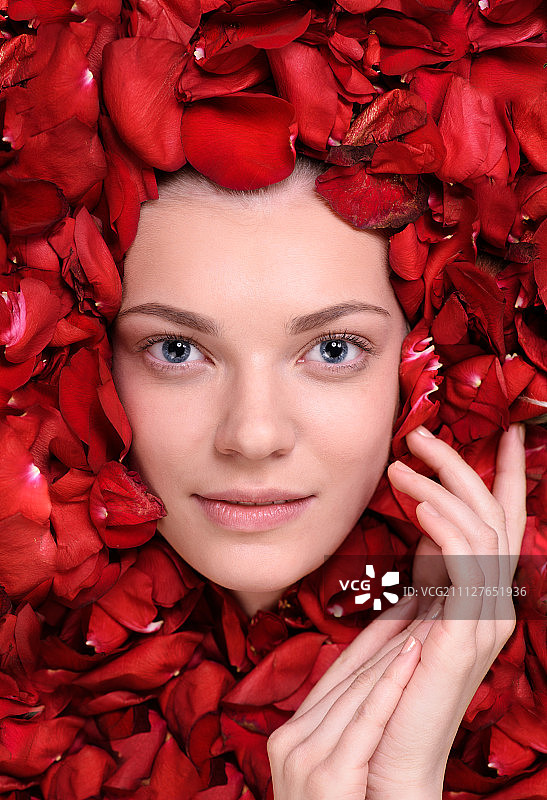 躺在玫瑰花瓣中的美丽快乐女人图片素材