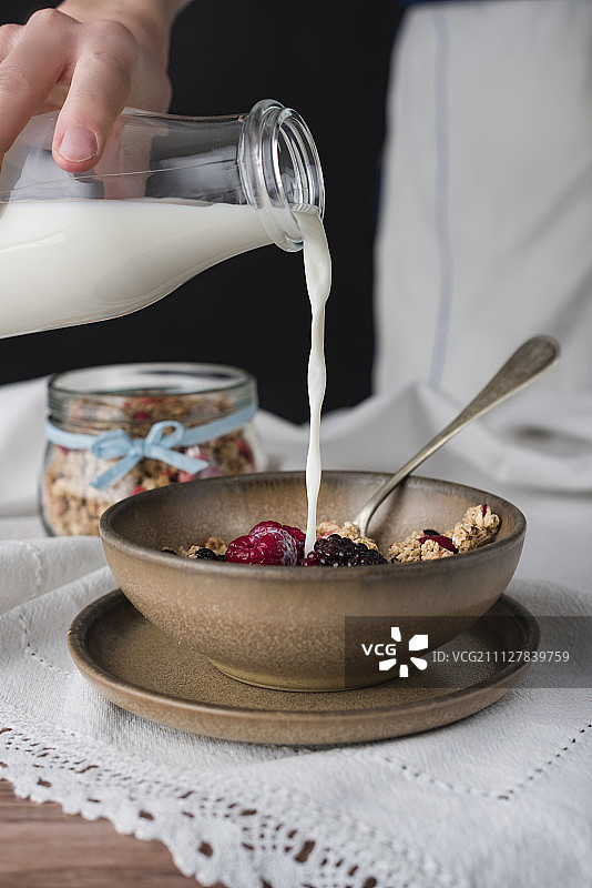 人类将牛奶倒入盛有麦片粥的碗中。图片素材