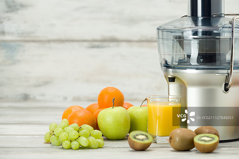 现代电动榨汁机、各种水果和一杯鲜榨果汁，健康生活方式概念图片素材