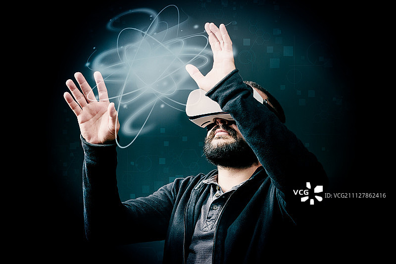 戴着VR眼镜的年轻时尚络腮胡男子，黑色背景工作室VR概念图片素材