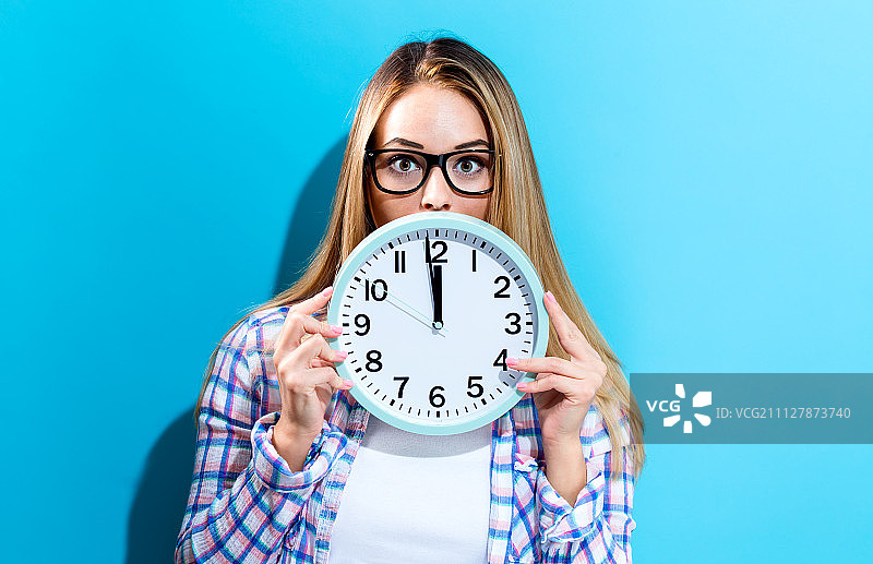 女人手持显示接近12点的时钟图片素材