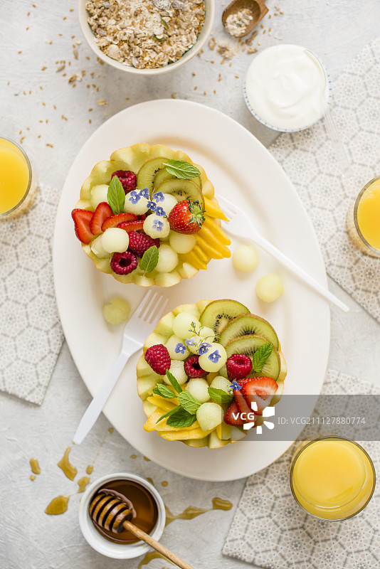 健康早餐：瓜类、酸奶、格兰诺拉麦片、橙汁和蜂蜜水果沙拉图片素材