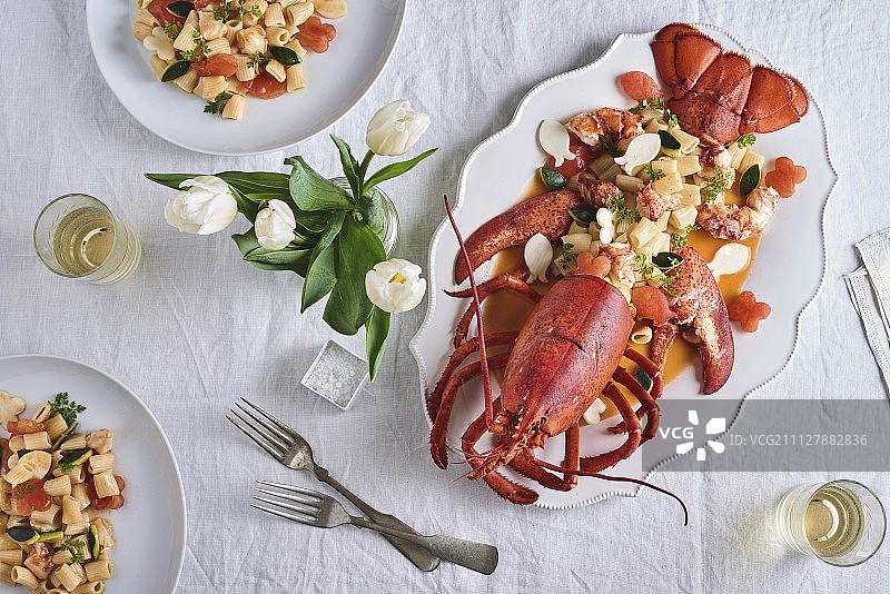 郁金香花瓶装饰的餐桌上的龙虾意面图片素材