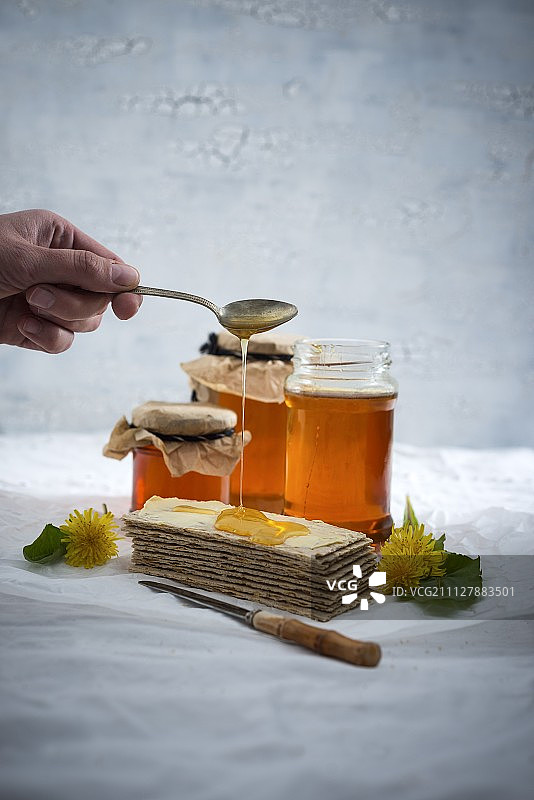 女人在脆面包上淋蒲公英糖浆图片素材