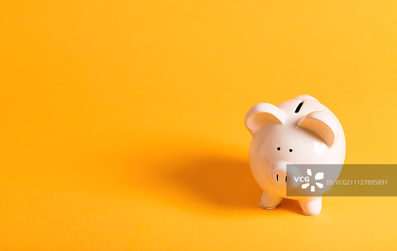 黄色背景上的白色小猪储蓄罐图片素材
