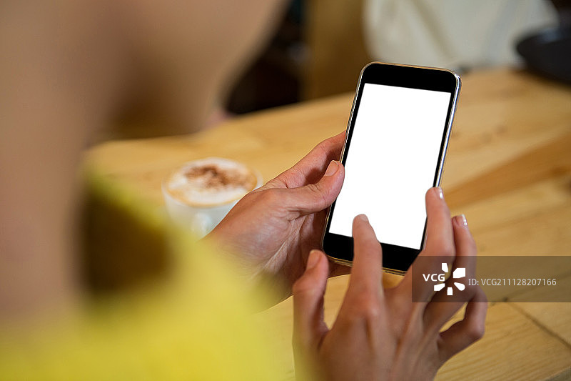 女人在咖啡店的桌旁使用手机的局部照片图片素材