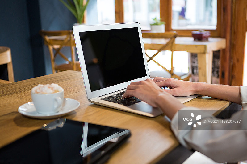 年轻女子在自助餐厅的桌旁使用笔记本电脑的局部照片图片素材