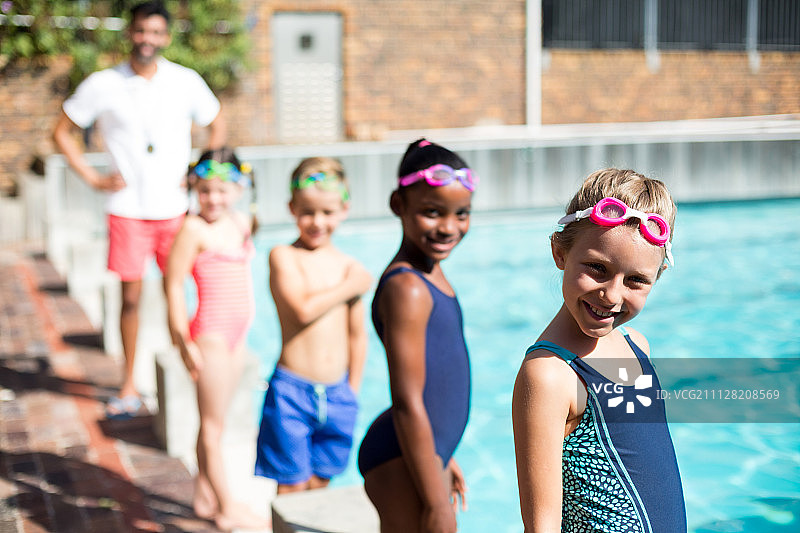 泳池边的小游泳者和男教练肖像图片素材