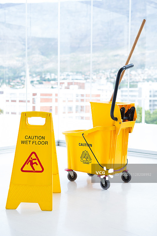 室内靠玻璃的指示牌和拖把桶图片素材