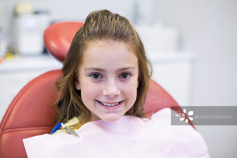 在牙科诊所坐在牙科椅上的微笑的年轻患者图片素材