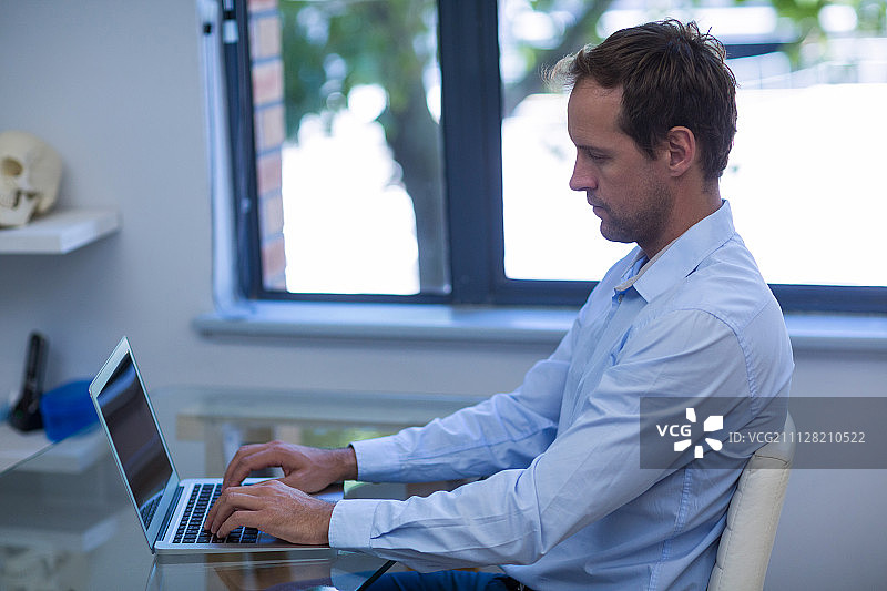 牙医在牙科诊所使用笔记本电脑图片素材