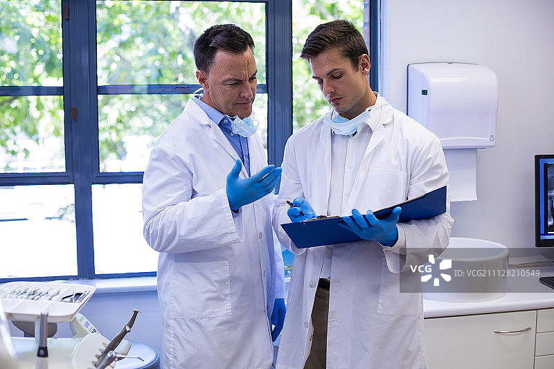 细心的牙医在诊所讨论报告图片素材