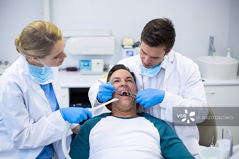 牙医在诊所用工具检查男病人图片素材