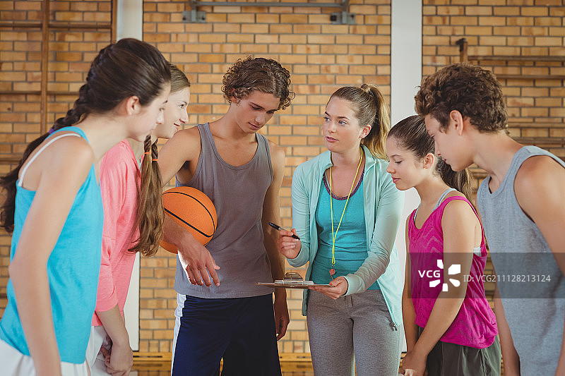 女教练在篮球场指导高中生图片素材