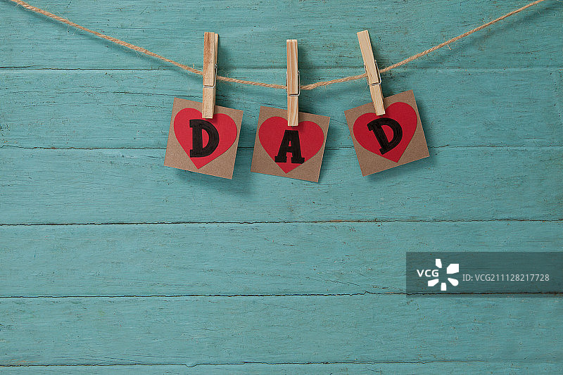 挂在绿色木墙上的心形老爸图片素材