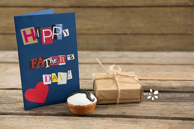 礼品和纸杯蛋糕在木桌上的特写贺卡图片素材
