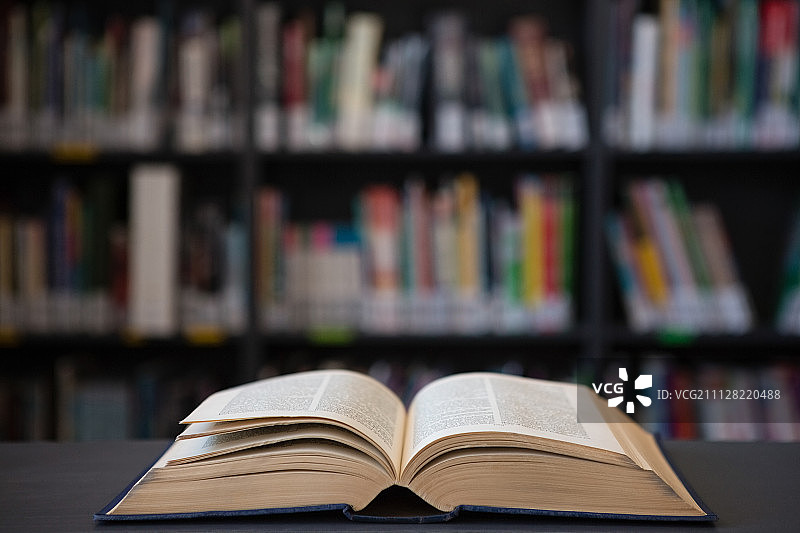 图书馆里桌子上打开的书的特写，背景是书架图片素材