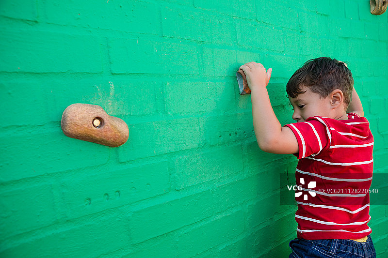 男孩在学校操场攀爬墙壁的背影图片素材