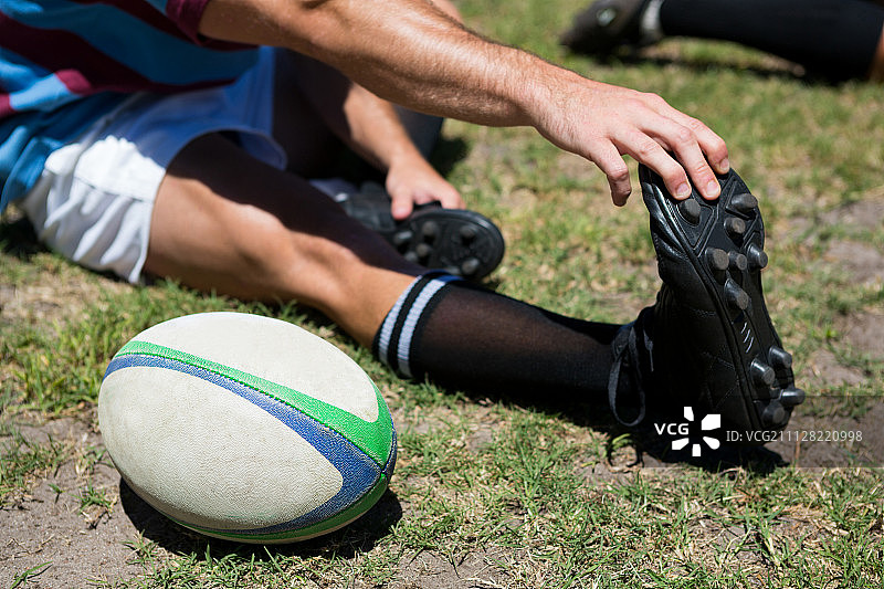 橄榄球运动员在草地上触摸脚趾的高角度视图图片素材