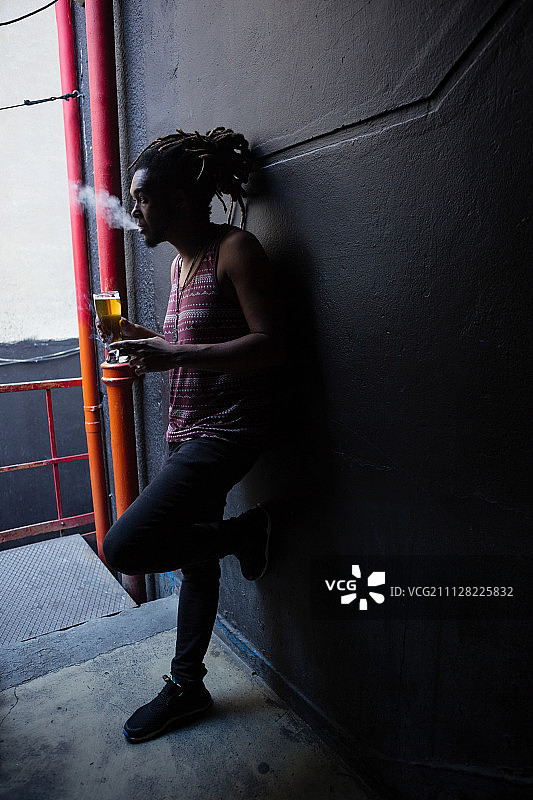 男人在酒吧入口处一边抽烟一边喝啤酒图片素材