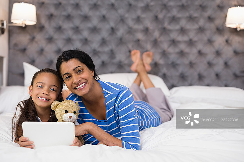 微笑的母亲和女儿在家用平板电脑图片素材
