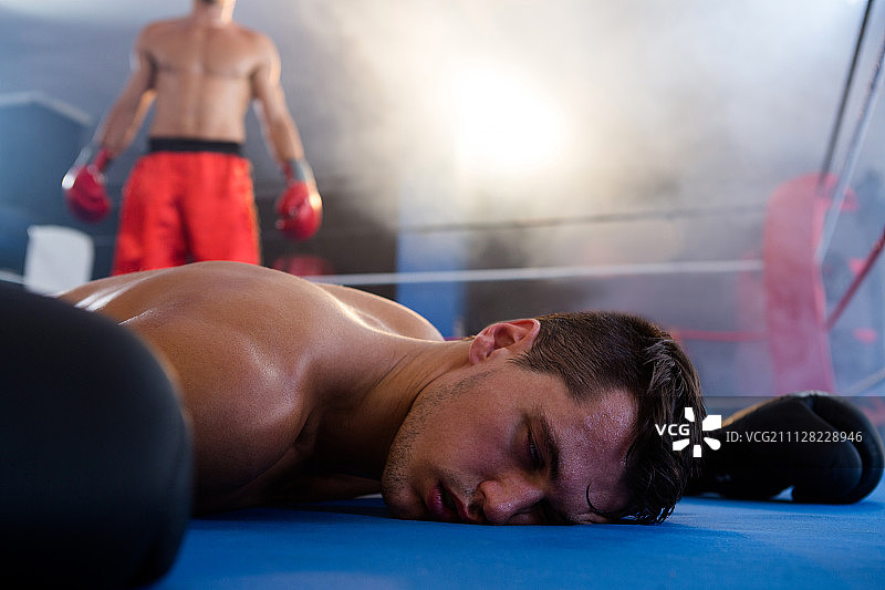 健身工作室拳击台上运动员身旁躺着失去知觉的男拳击手图片素材