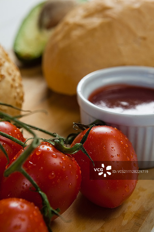 小圆面包、樱桃番茄和酱汁在砧板上的特写图片素材