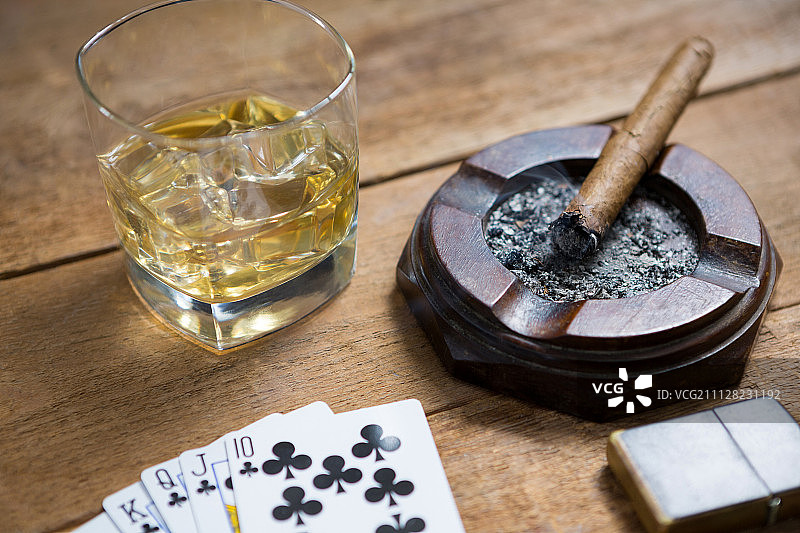 威士忌、雪茄和纸牌在木桌上的特写图片素材