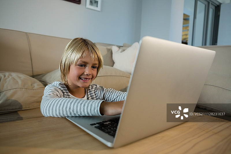 男孩在客厅使用笔记本电脑图片素材