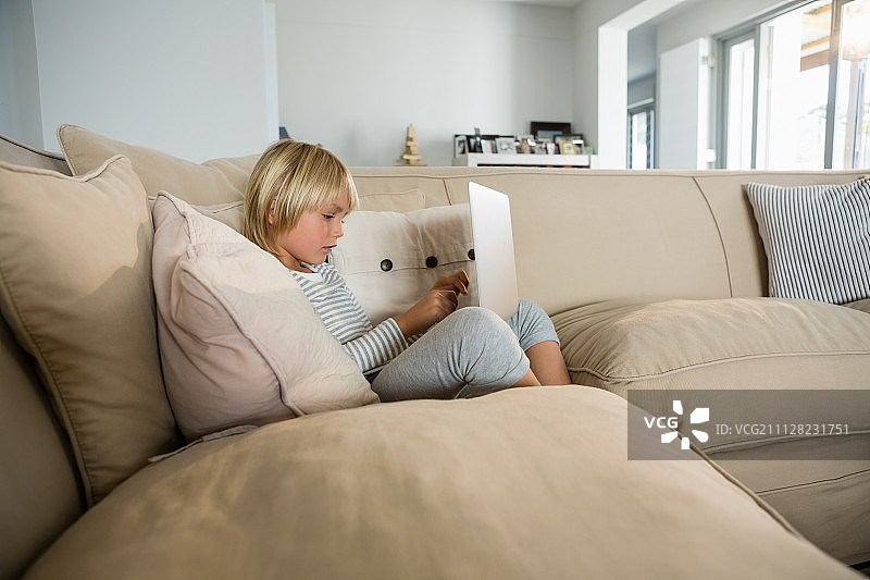 男孩在客厅使用笔记本电脑图片素材