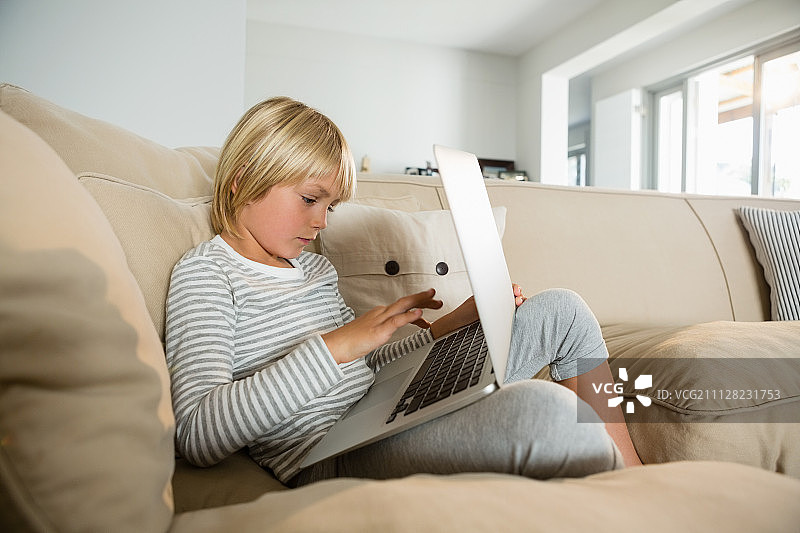 男孩在客厅使用笔记本电脑图片素材