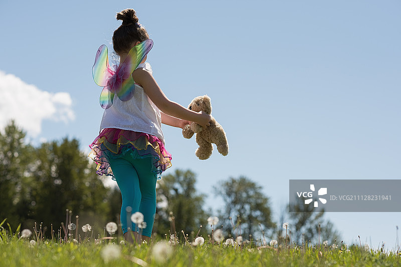 微笑的女孩在公园里玩泰迪熊图片素材