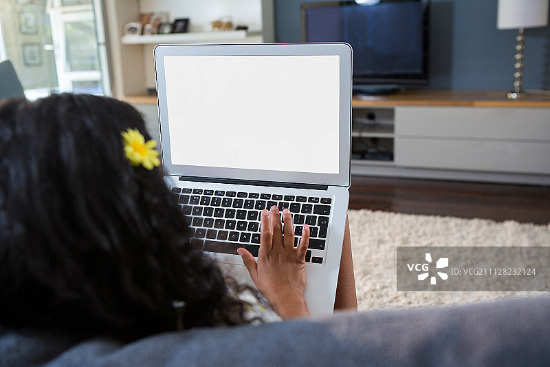 女孩在沙发上使用笔记本电脑的背影图片素材