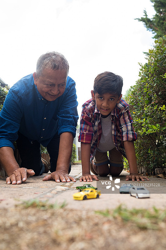 男孩和爷爷在院子里玩玩具车图片素材