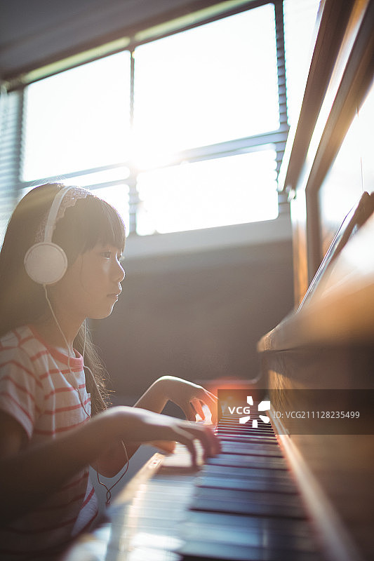 专注的女孩在音乐学校的教室里用平板电脑练习钢琴图片素材