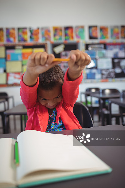 女学生坐在教室的课桌旁伸展双手图片素材