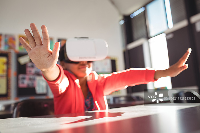 在学校教室里，女孩戴着VR眼镜做手势图片素材